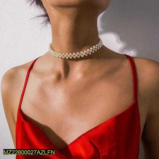 Person wearing a pearl choker necklace and red top against a neutral background