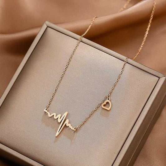 Gold necklace with heart and heartbeat design on a beige box