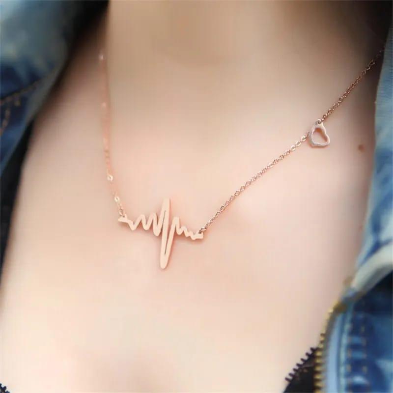 Rose gold necklace with heart and line design on a person wearing a blue denim jacket.