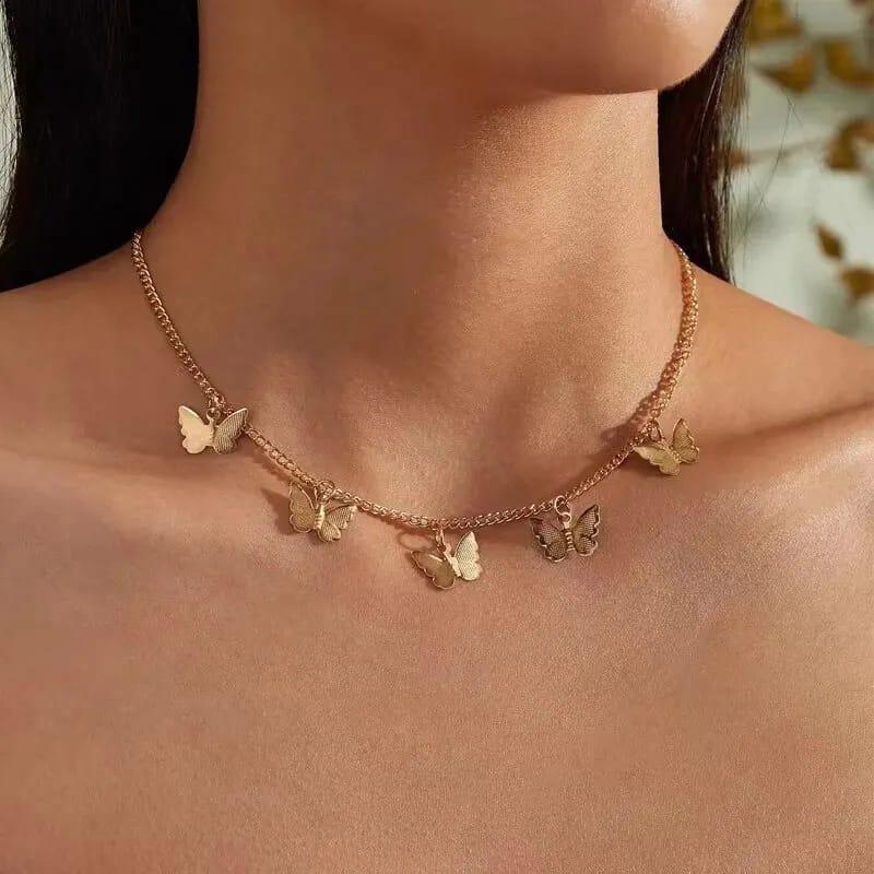 Gold butterfly necklace on a person's neck with a blurred natural background