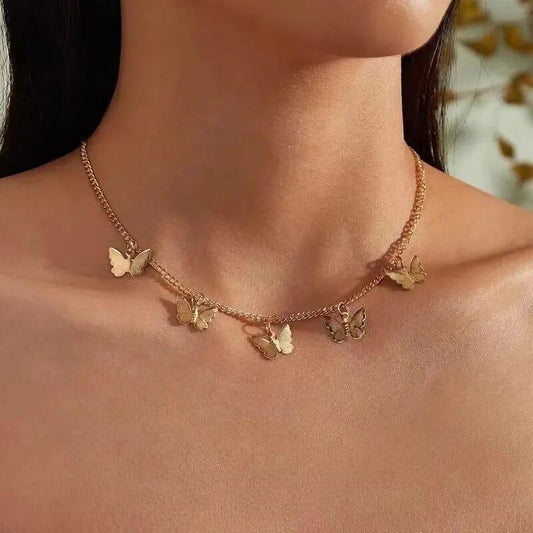 Gold butterfly necklace on a person's neck with a blurred natural background