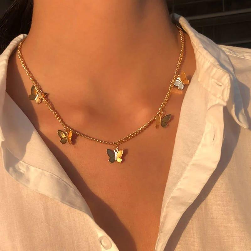Gold butterfly necklace on a person wearing a light-colored shirt.