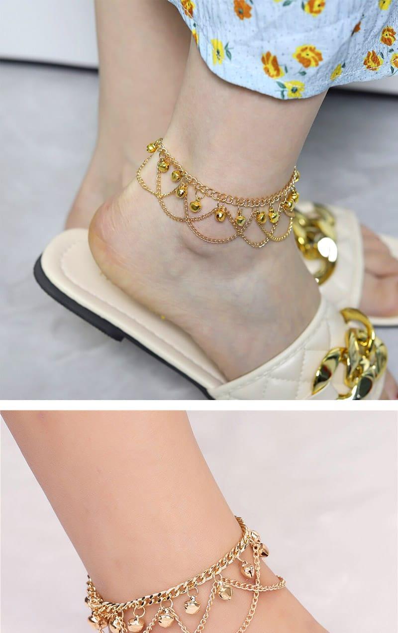 Gold anklets on feet with a neutral background