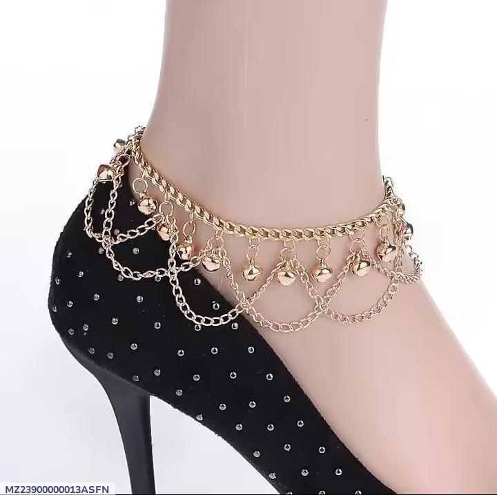 Gold anklet with chains and small bells on a black stiletto shoe.