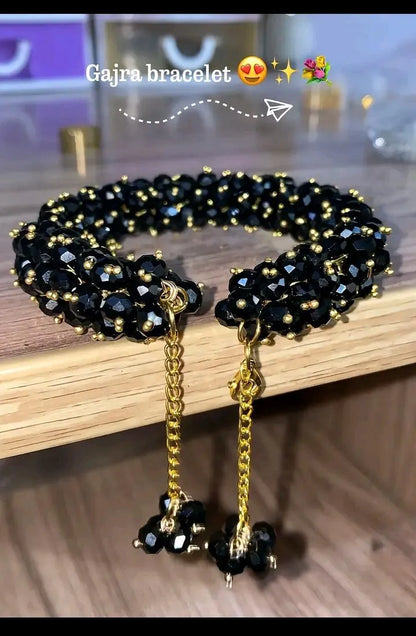 Black beaded bracelet with gold chain on a wooden surface