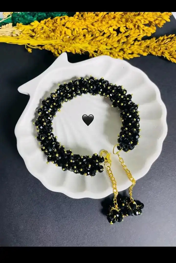 Black beaded necklace with gold chain on a white shell against a dark background