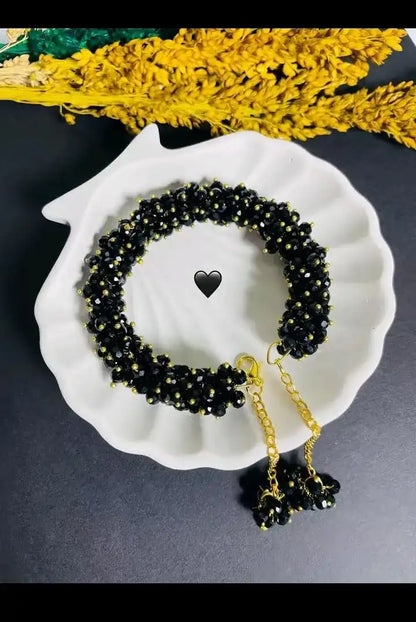Black beaded necklace with gold chain on a white shell against a dark background