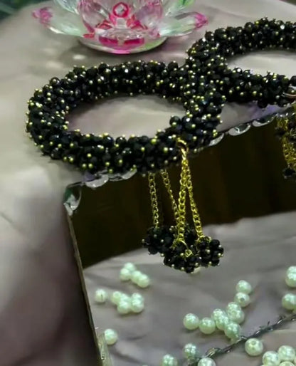 Black beaded necklace with gold accents on a reflective surface