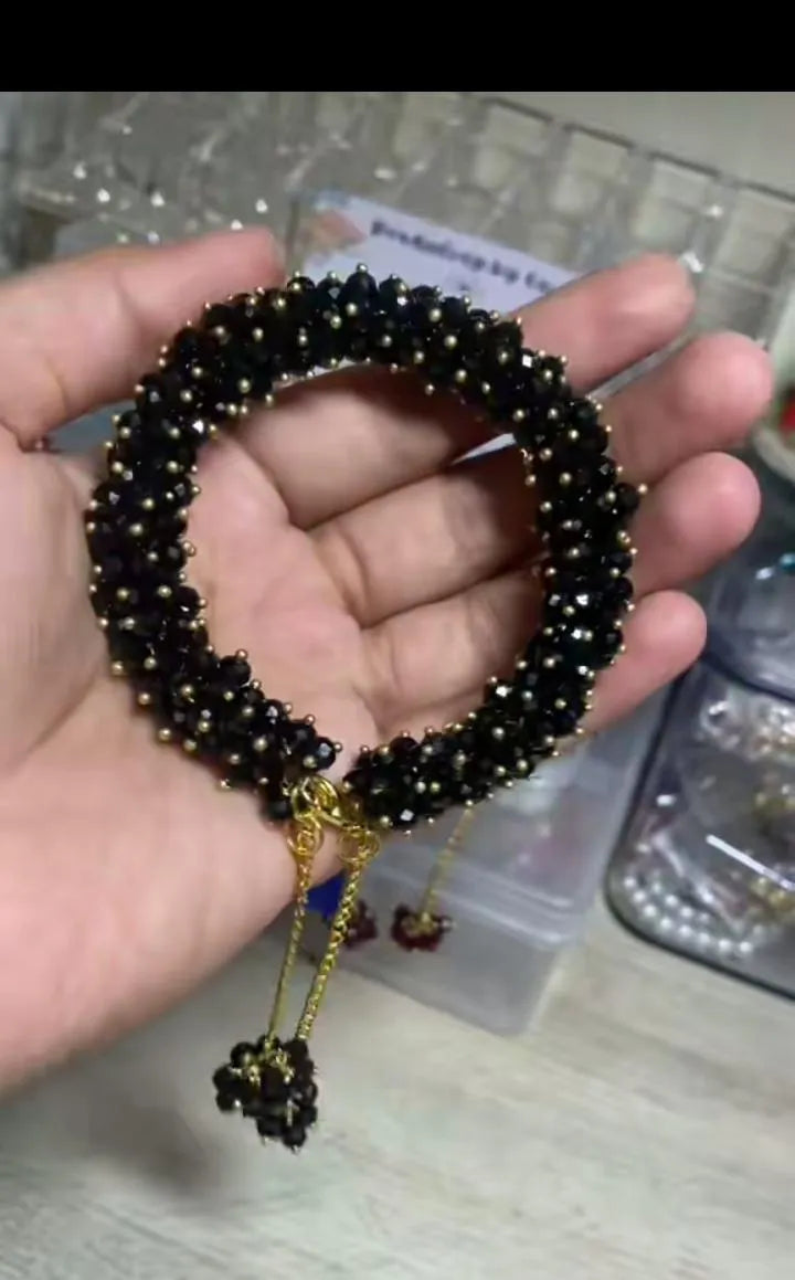 Black beaded bracelet held in a hand with a blurred background