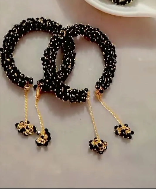 Black beaded bracelets with gold accents on a light gray surface