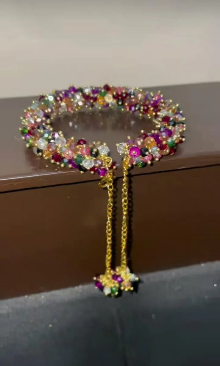 Multicolored beaded bracelet with a matching earring on a reflective surface.