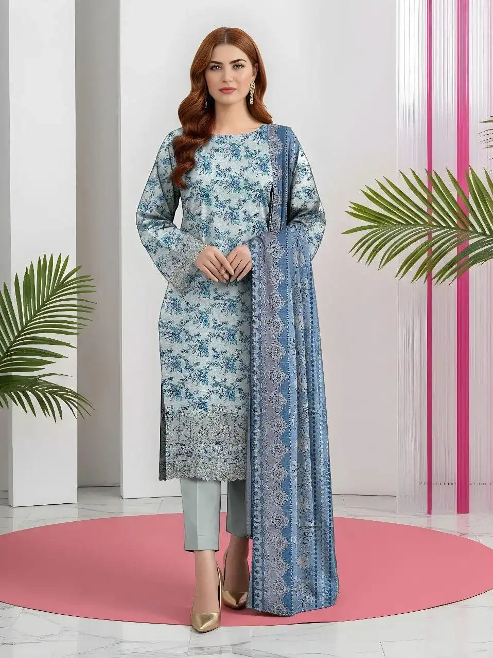 Woman wearing a blue floral dress with a matching dupatta in a minimalistic setting.