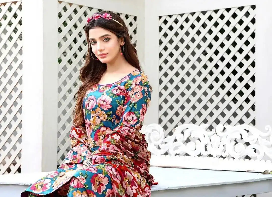 Woman wearing a colorful floral dress sitting on a white lattice bench.