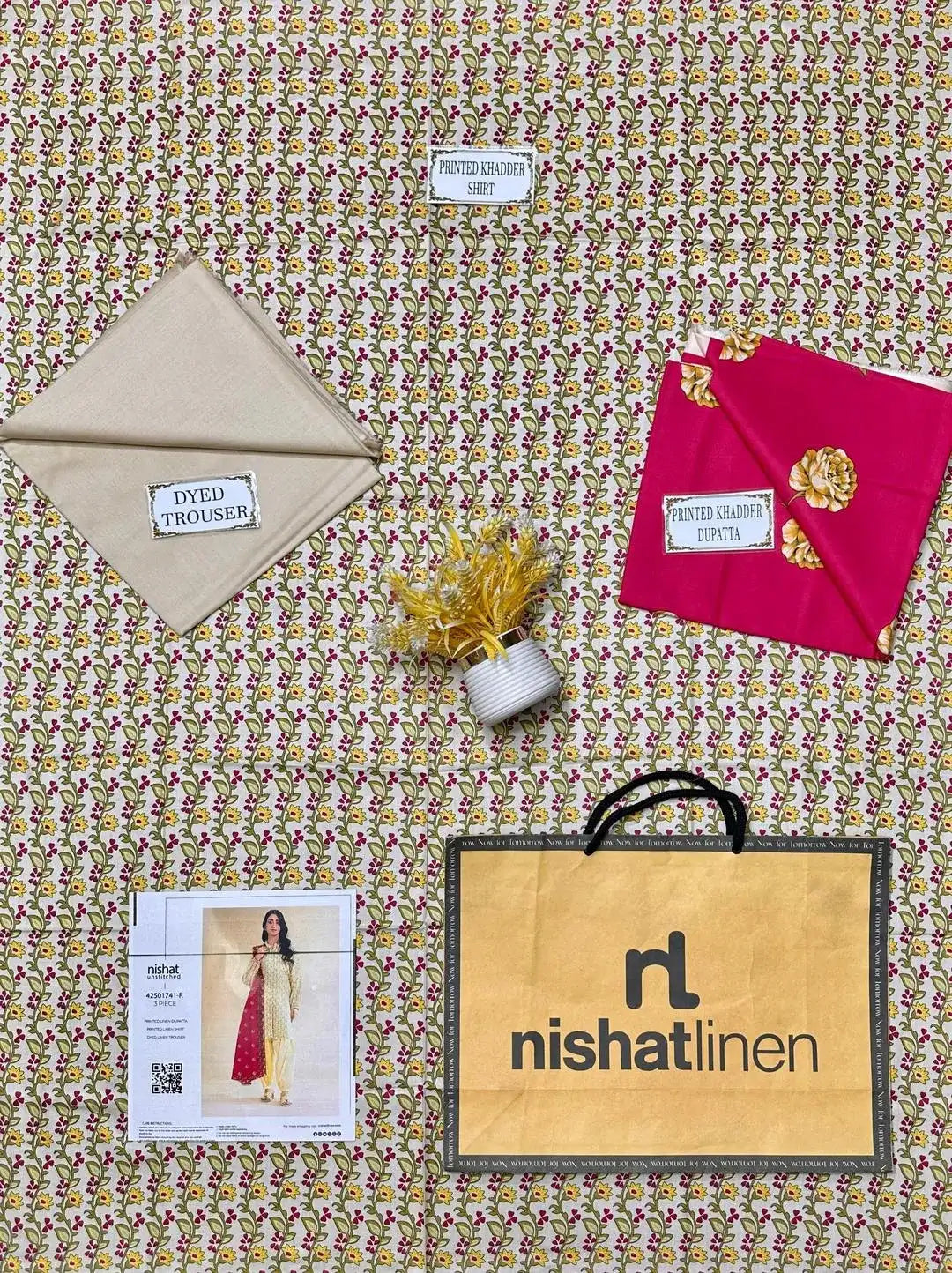 Fabric samples and a Nishat Linen bag on a patterned fabric background