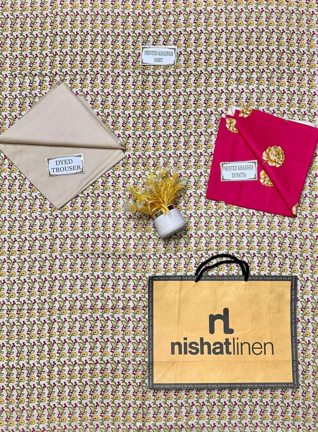 Fabric samples and a Nishat Linen bag on a patterned fabric background