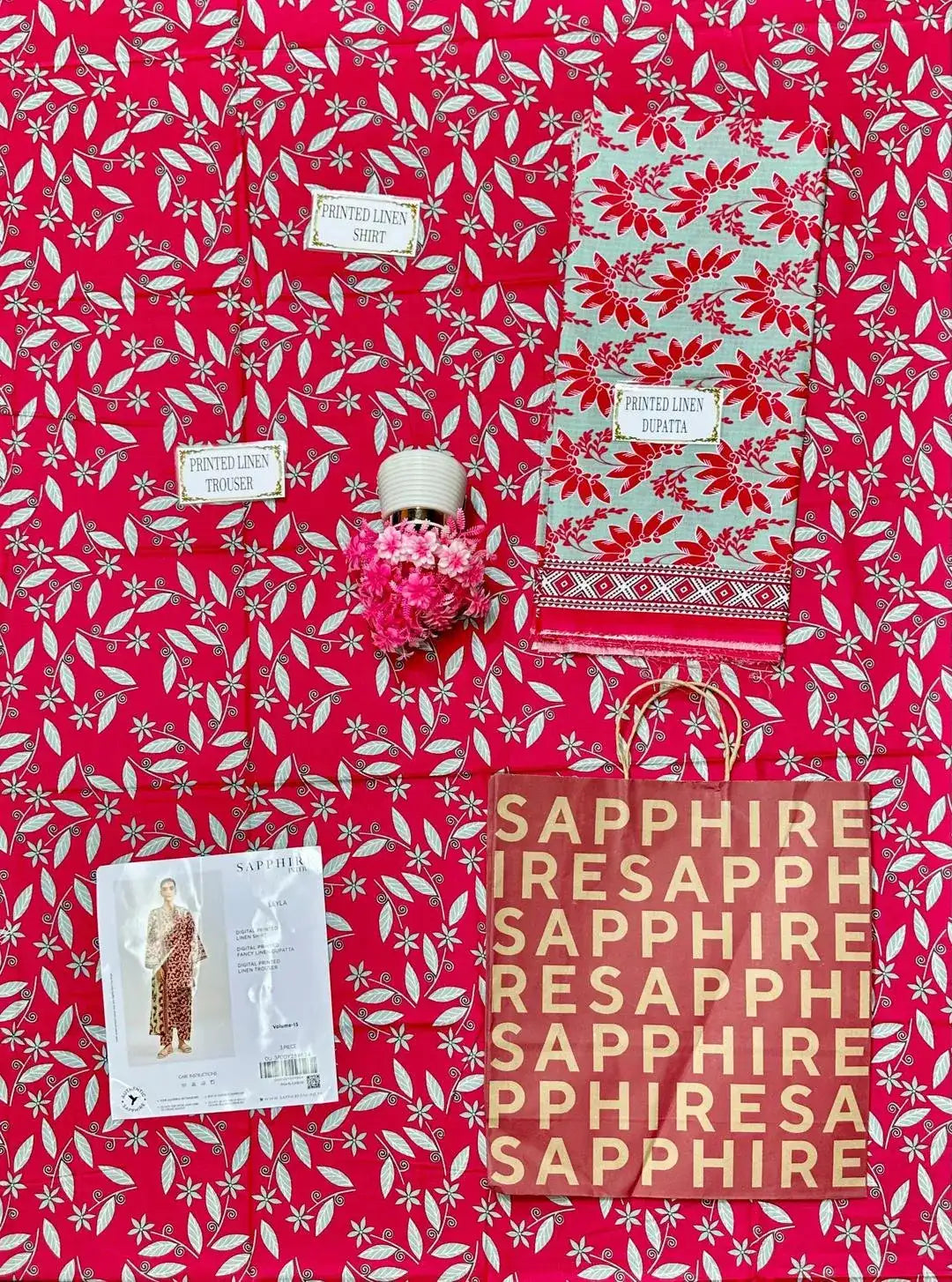 Red and white patterned fabric with 'Sapphire' branding and a small decorative item.