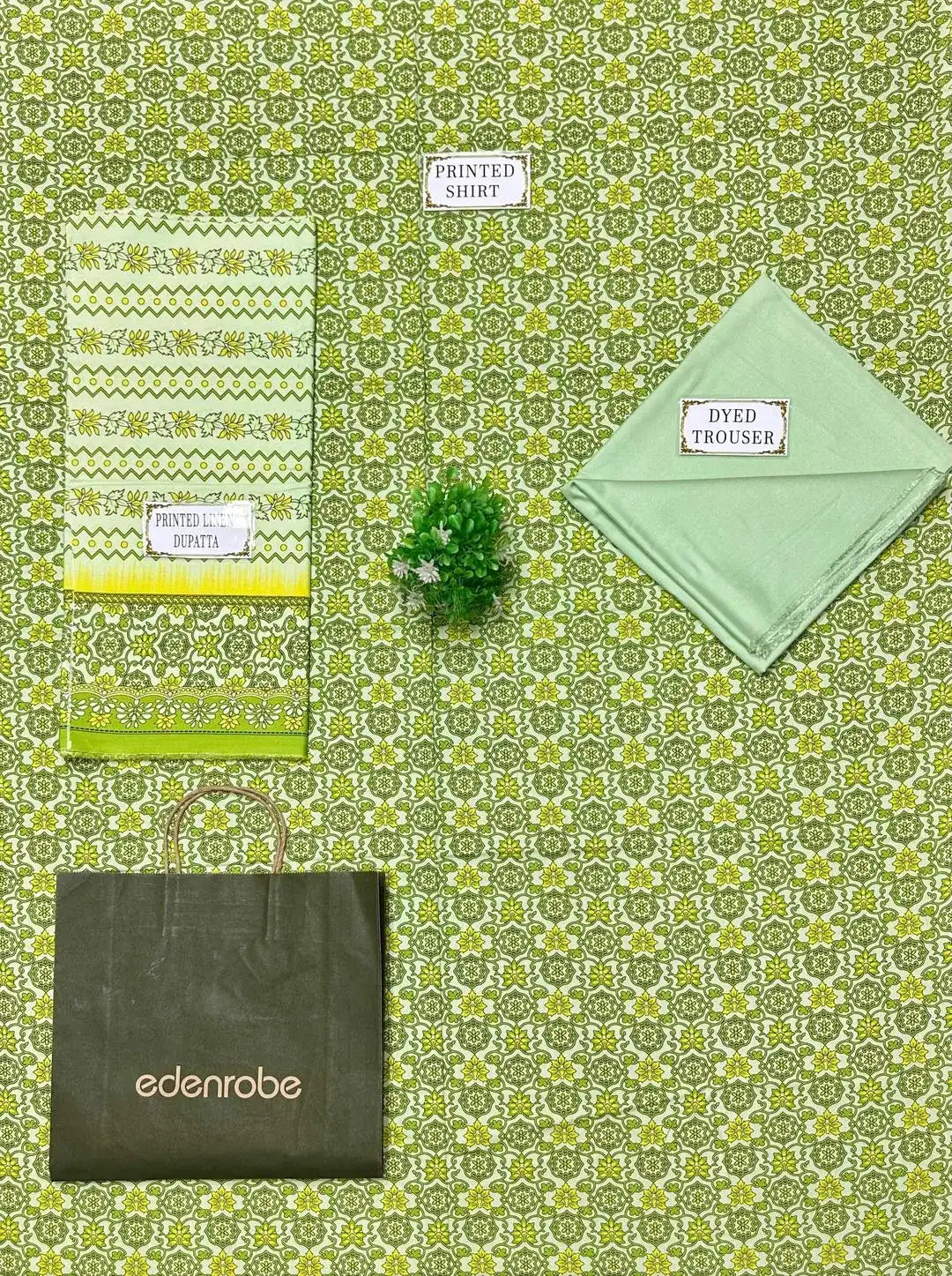 Collection of green clothing and accessories on a green patterned background with 'edenrobe' branding.