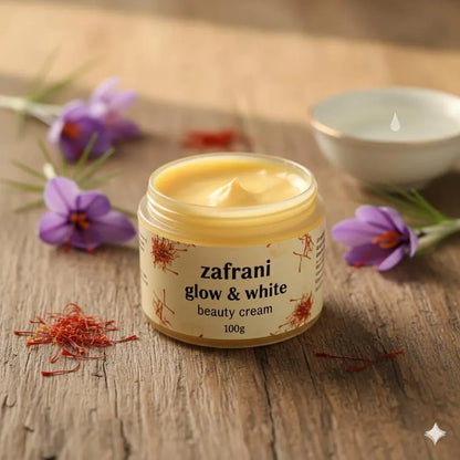 Jar of zafrani glow & white beauty cream on a wooden surface with saffron and flowers.