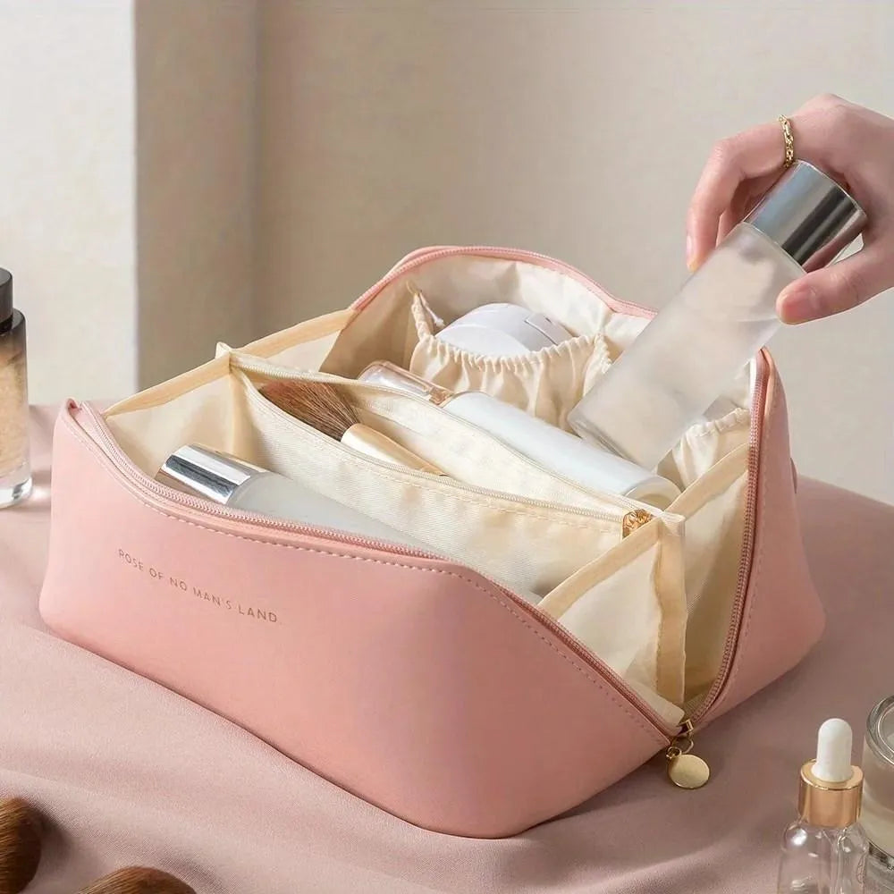 Pink cosmetic bag with organized compartments and a hand holding a bottle over it.