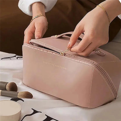 Person opening a pink cosmetic bag with makeup brushes on a table