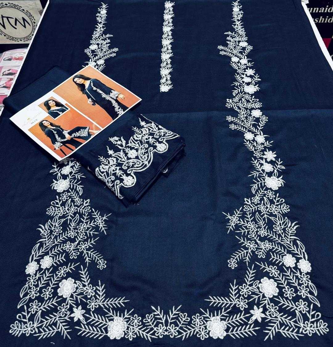 Navy blue fabric with white floral embroidery, folded clothes, and a magazine on top.