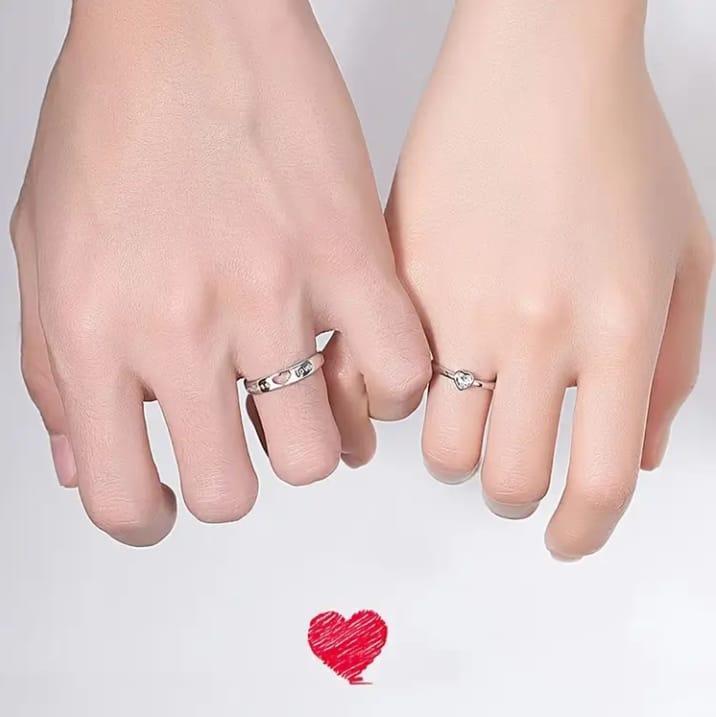 Two hands with silver rings on a white background with a red heart.