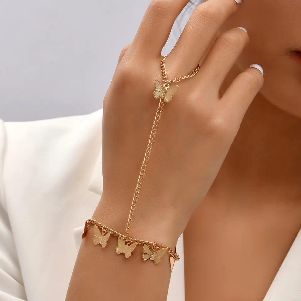 Gold bracelet with butterfly charms on a hand against a neutral background