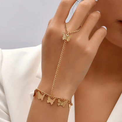 Gold bracelet with butterfly charms on a hand against a neutral background