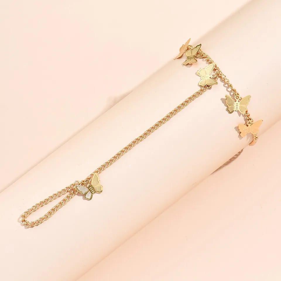 Gold butterfly anklet on a pink background