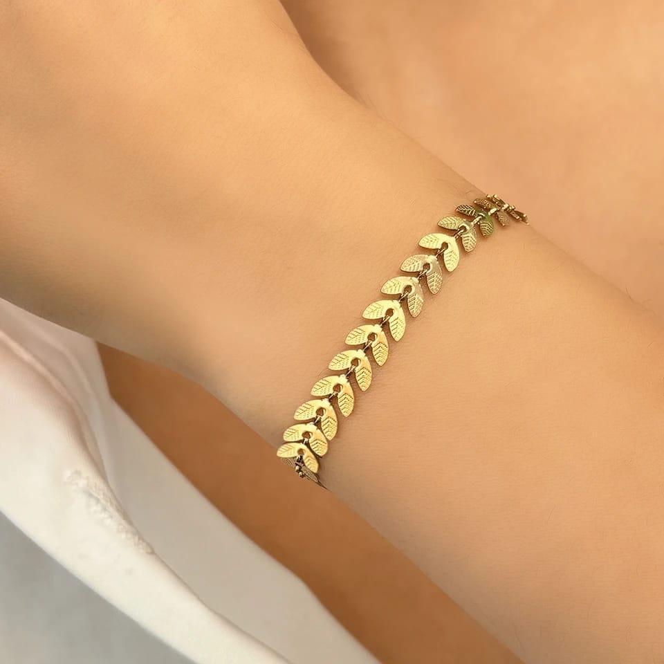Gold bracelet on a person's wrist with a neutral background