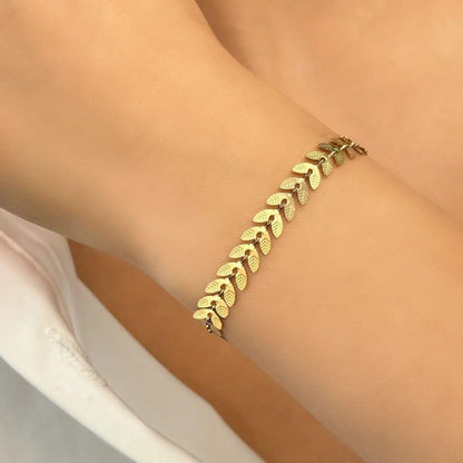 Gold bracelet on a person's wrist with a neutral background