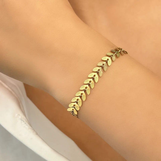 Gold bracelet on a person's wrist with a neutral background