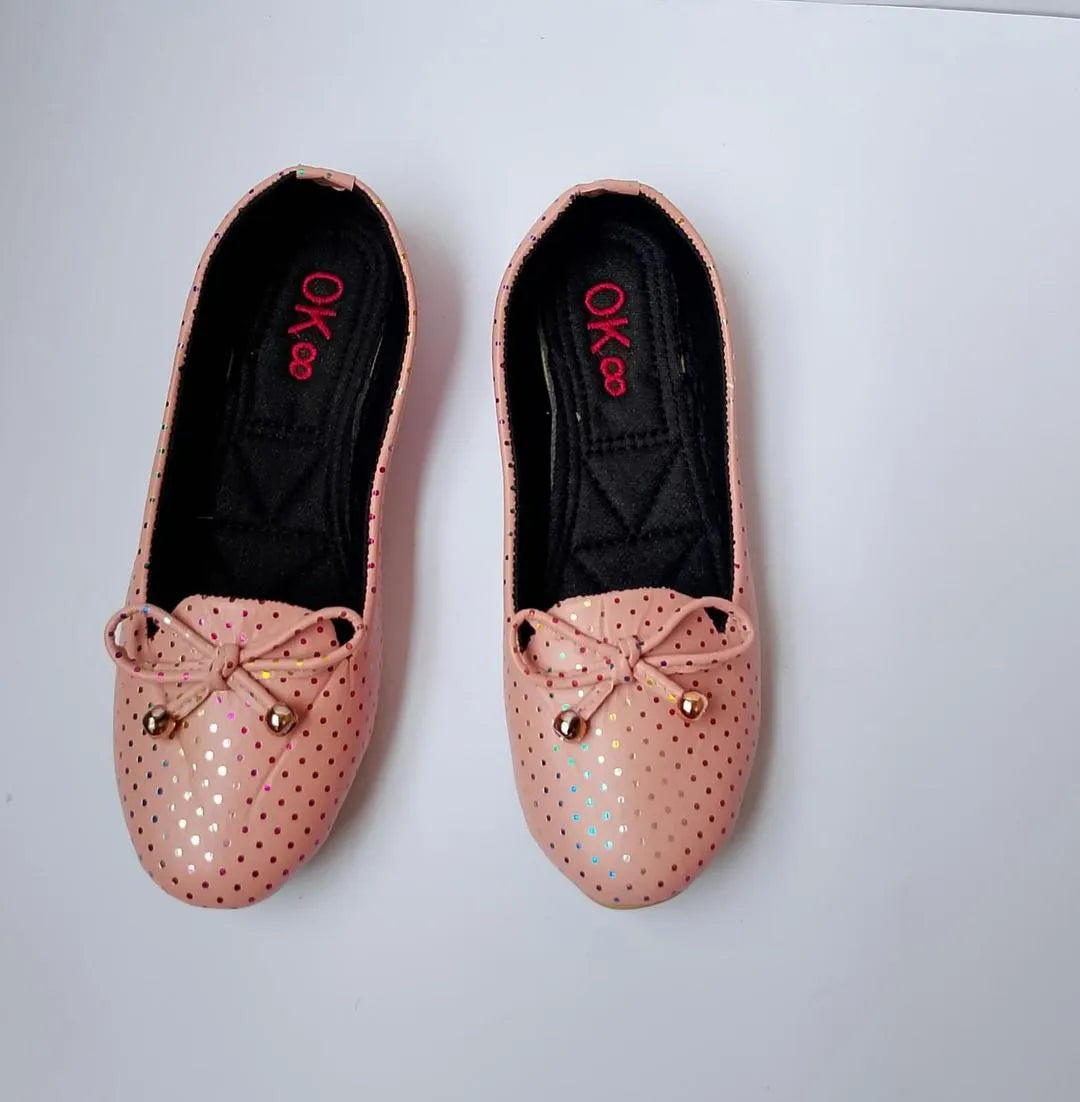 Pair of pink glittery shoes with decorative bows on a light gray background