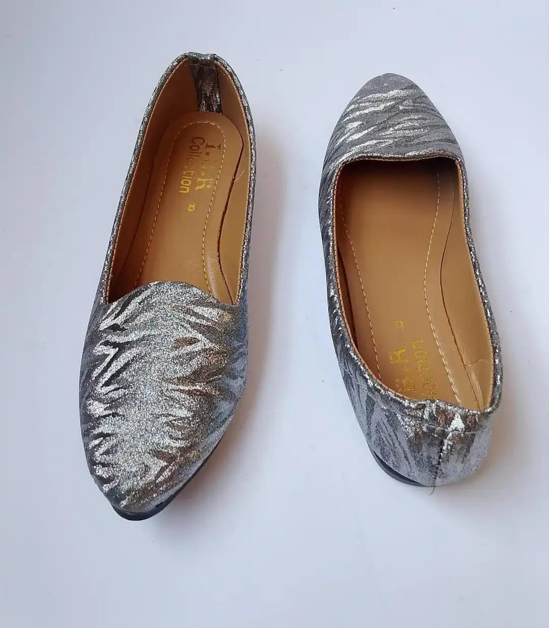 Pair of silver glittery flats on a white background