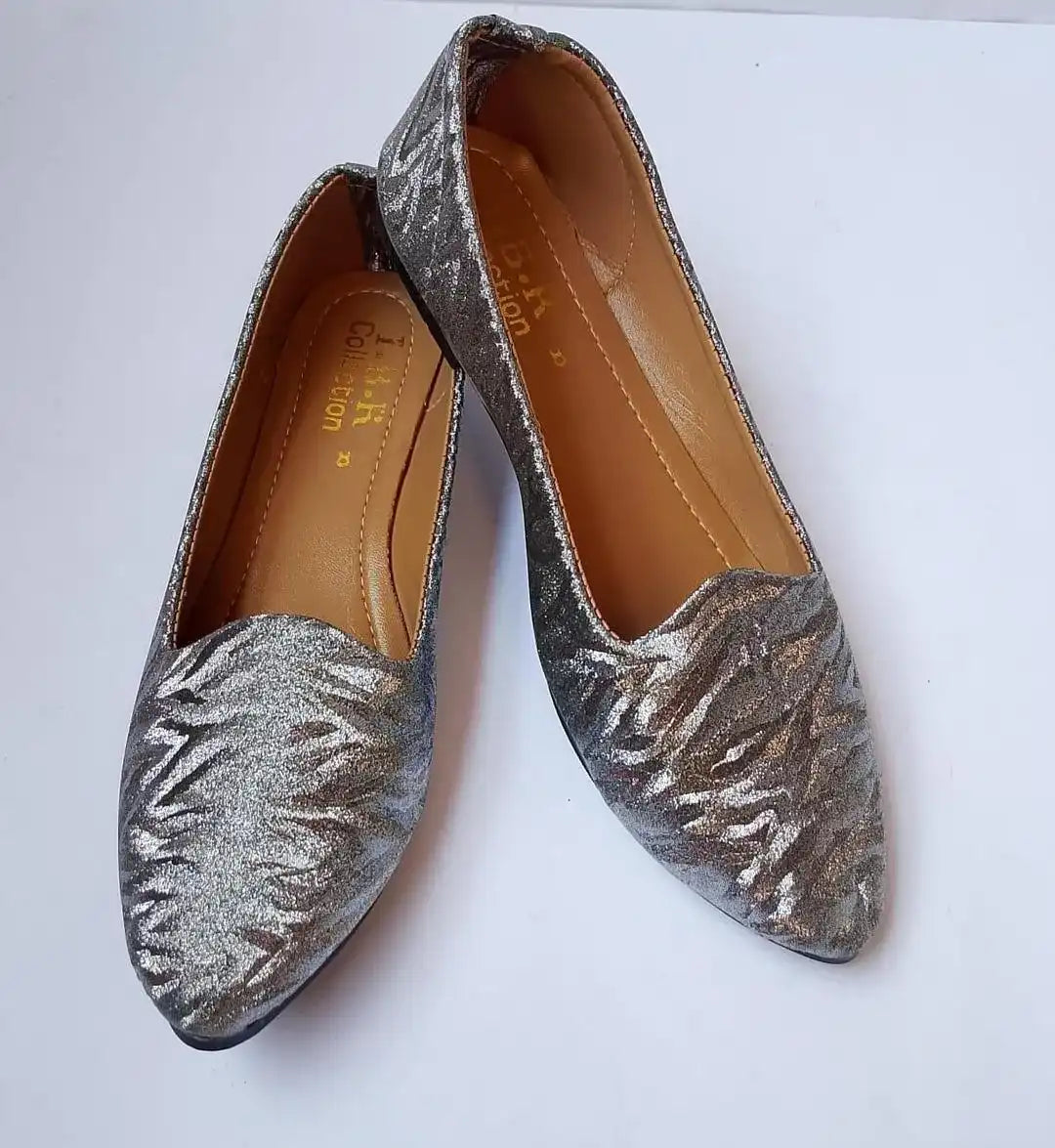 Pair of silver glittery flats on a white background