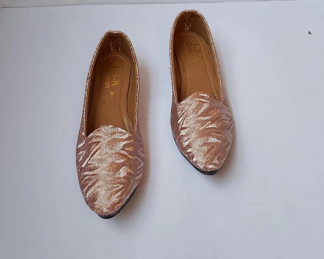 Pair of rose gold loafers on a white background