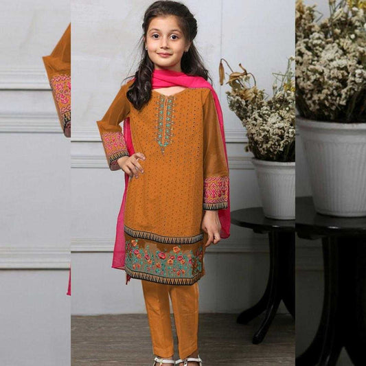 Young girl wearing an orange embroidered outfit with a pink scarf indoors.