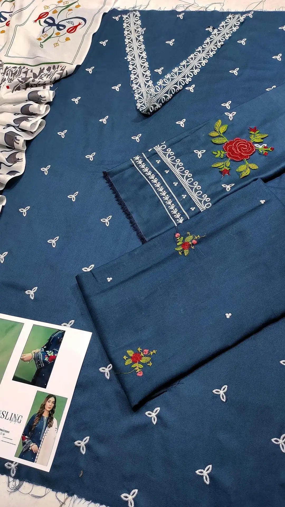 Blue fabric with white embroidery and floral patterns, displayed with a magazine.