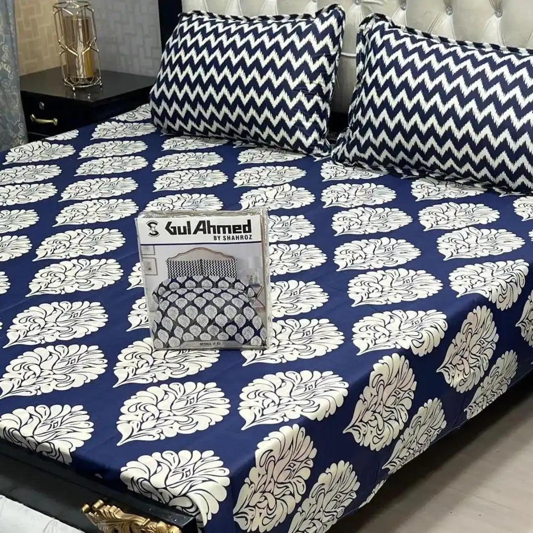Bed with blue and white patterned bedspread and pillows, featuring a magazine titled 'Gul Ahmed'.
