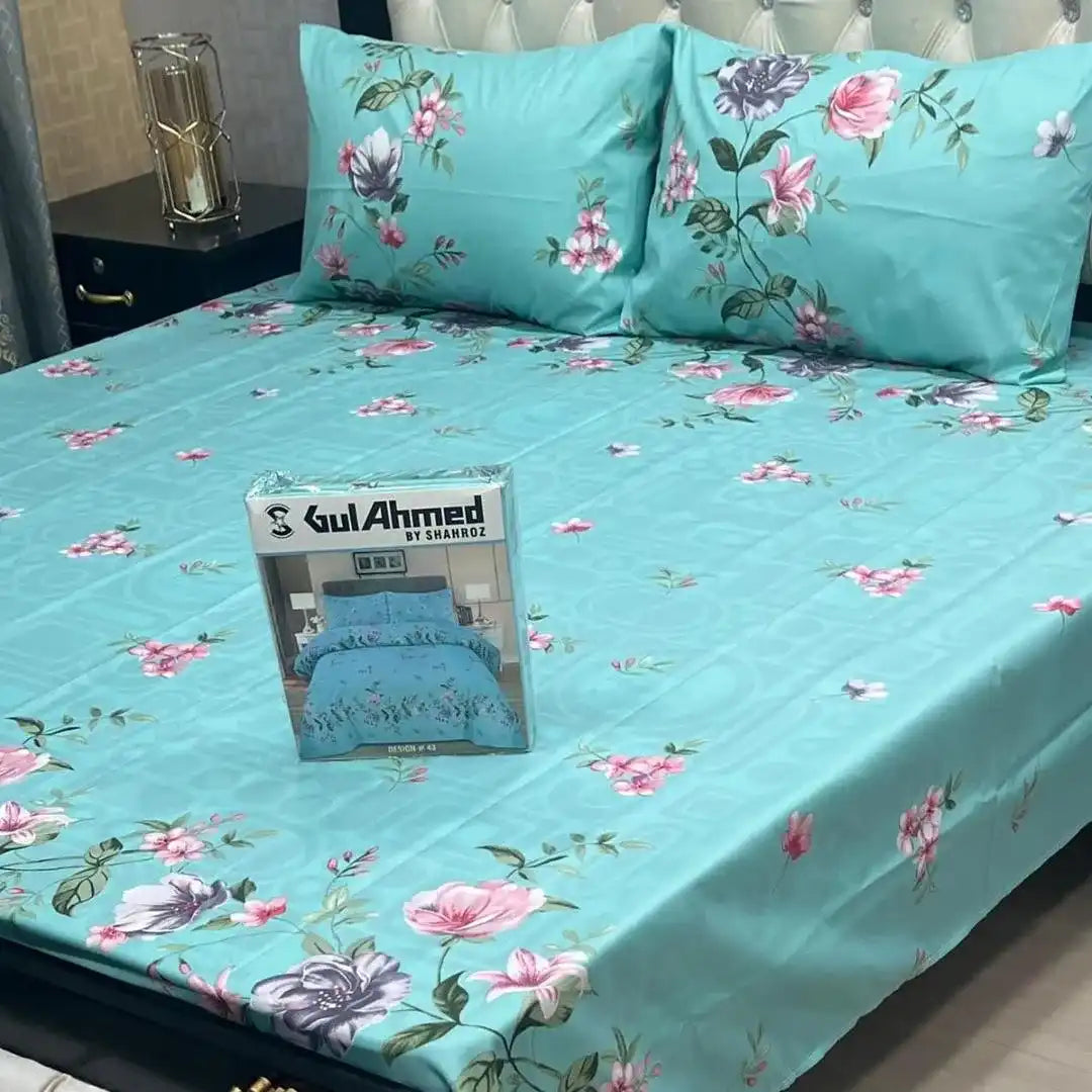 Floral bedsheet set with matching pillows on a bed, featuring a Gul Ahmed product packaging.