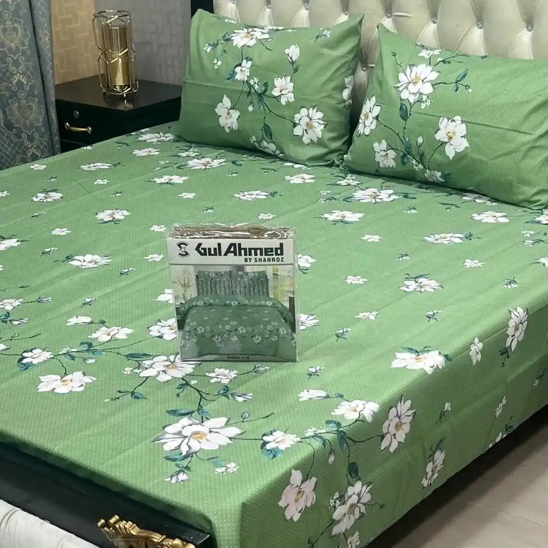 Green floral bedsheet with matching pillows on a bed, featuring Gul Ahmed packaging.