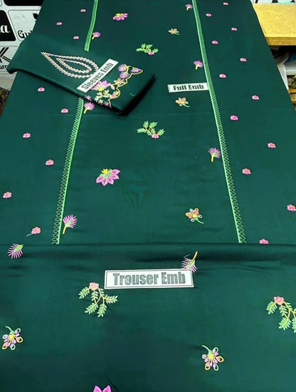 Green fabric with floral embroidery and 'Trouser Emb' label on a table.