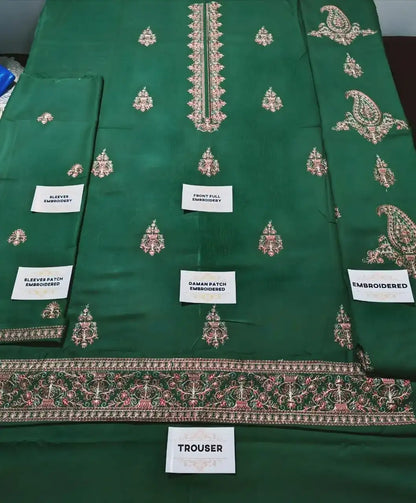 Green embroidered fabric with labels indicating parts of a garment