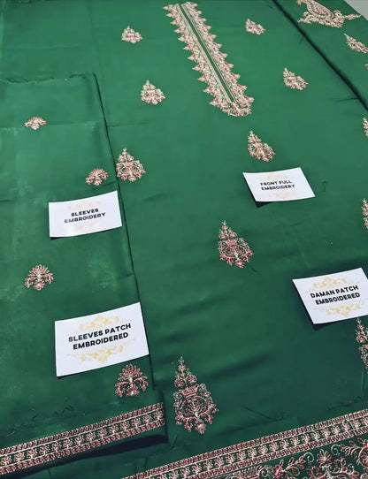 Green fabric with embroidered patterns and labels indicating embroidery details.