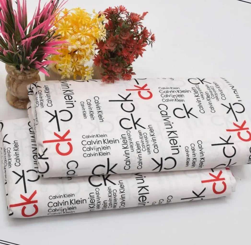 Rolls of Calvin Klein fabric with flowers in the background