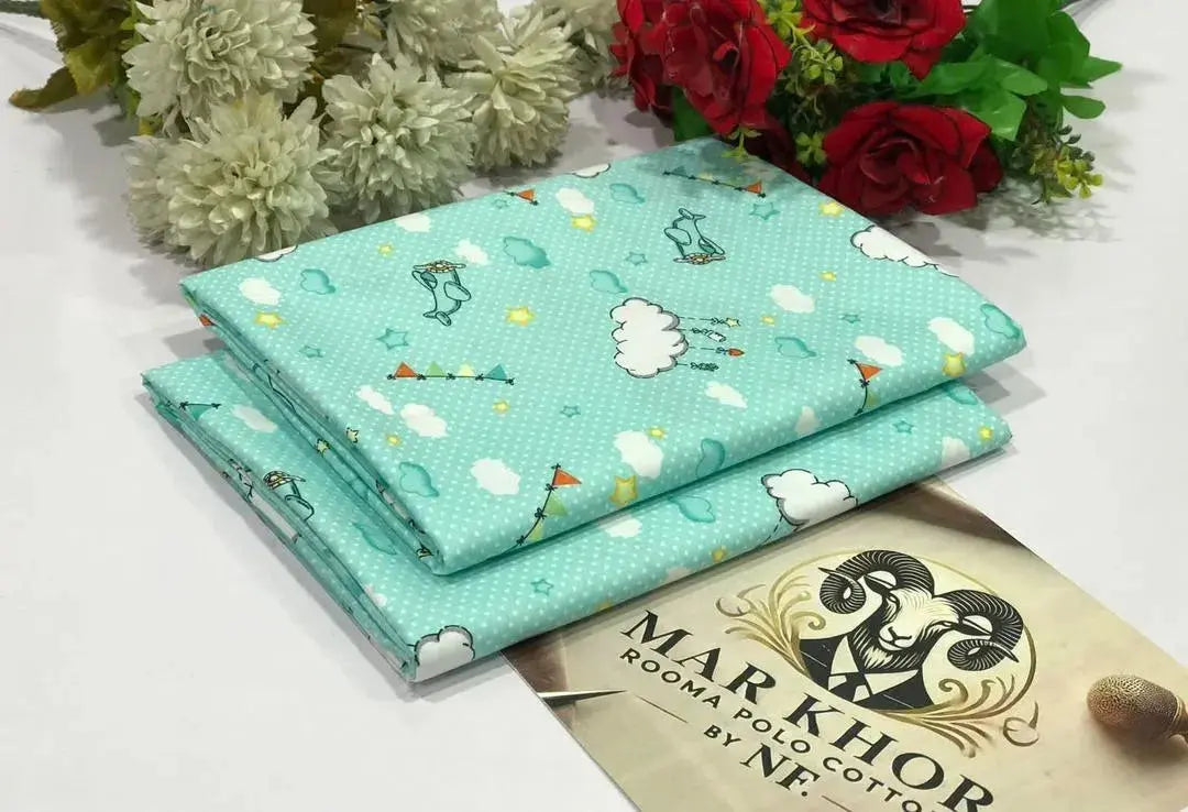 Two pieces of fabric with cartoon designs on a surface with flowers and a brand name visible.