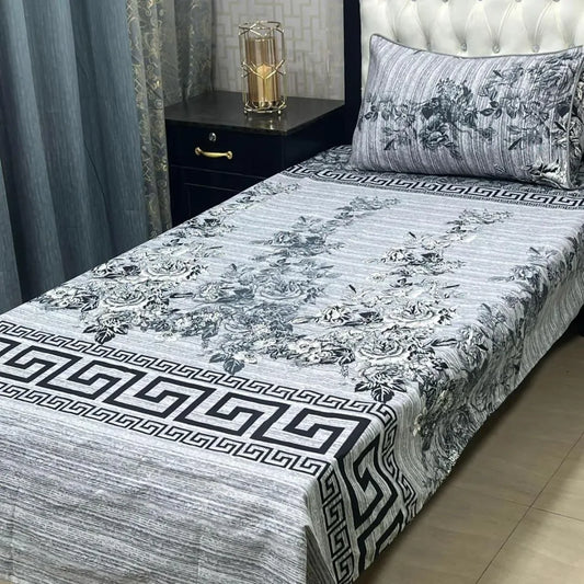 Bed with floral patterned bedspread and matching pillow in a bedroom setting.