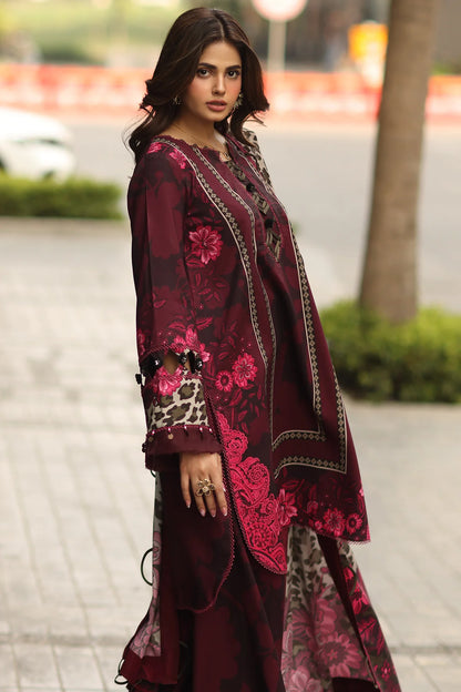 Woman wearing a maroon embroidered traditional outfit with a blurred outdoor background