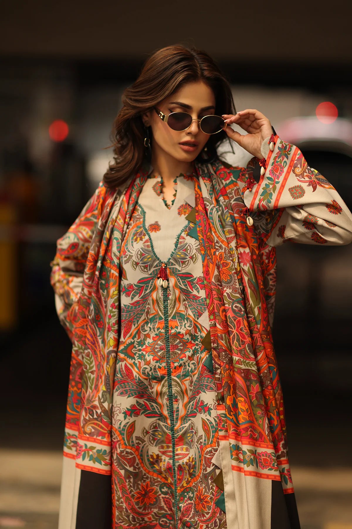 Woman wearing a colorful patterned outfit with sunglasses in an urban setting