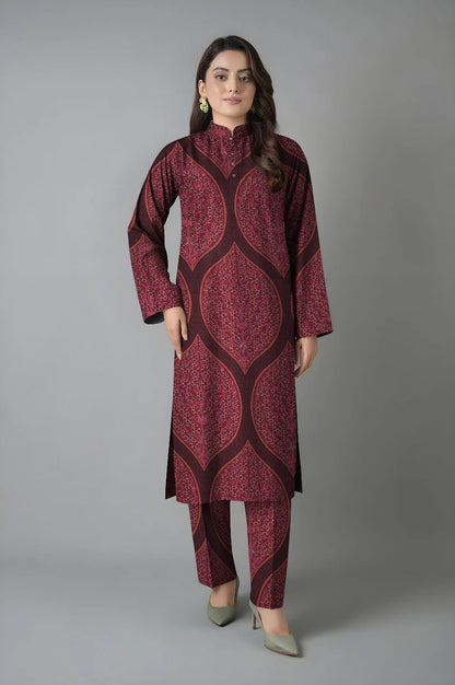 Woman wearing a maroon patterned kurta with pants against a gray background